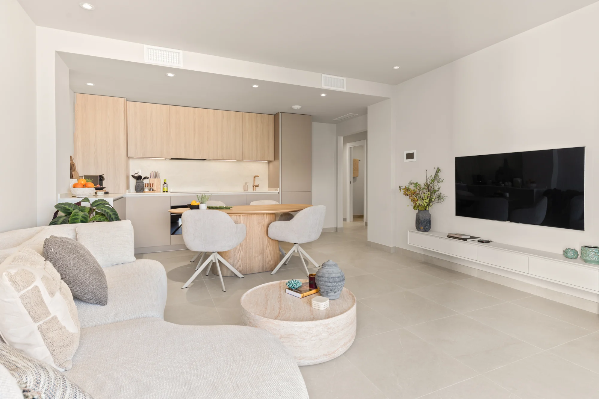 Bright open-plan living room with curved sofa, oak dining table and fully fitted kitchen