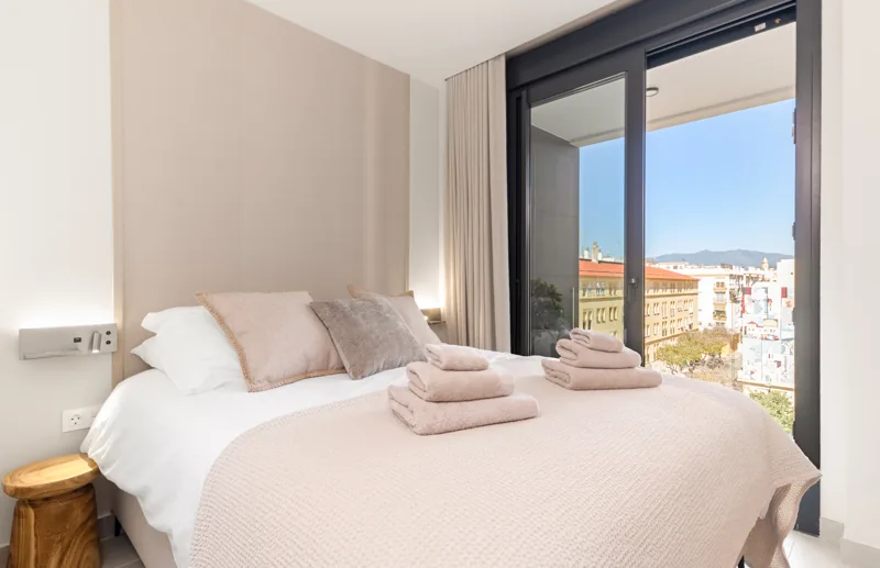 Principal bedroom with soft neutral bedding and balcony doors